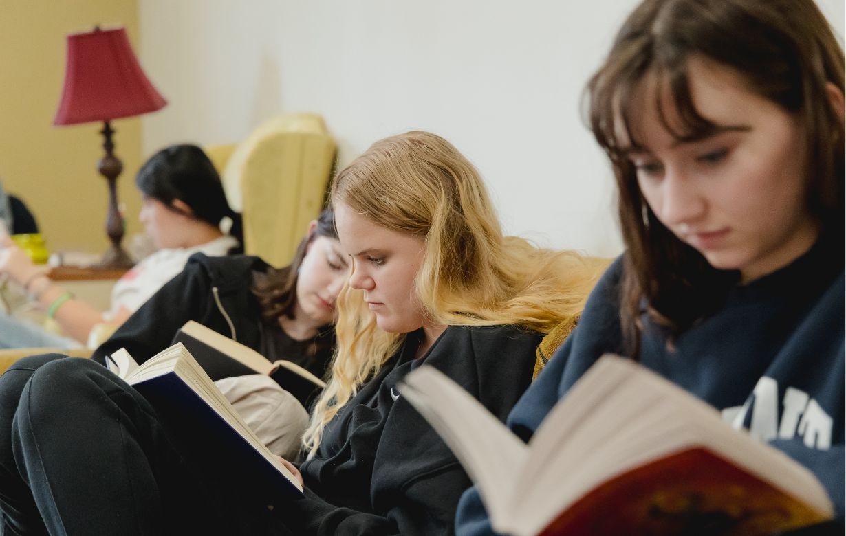 Three female students on a couch reading books