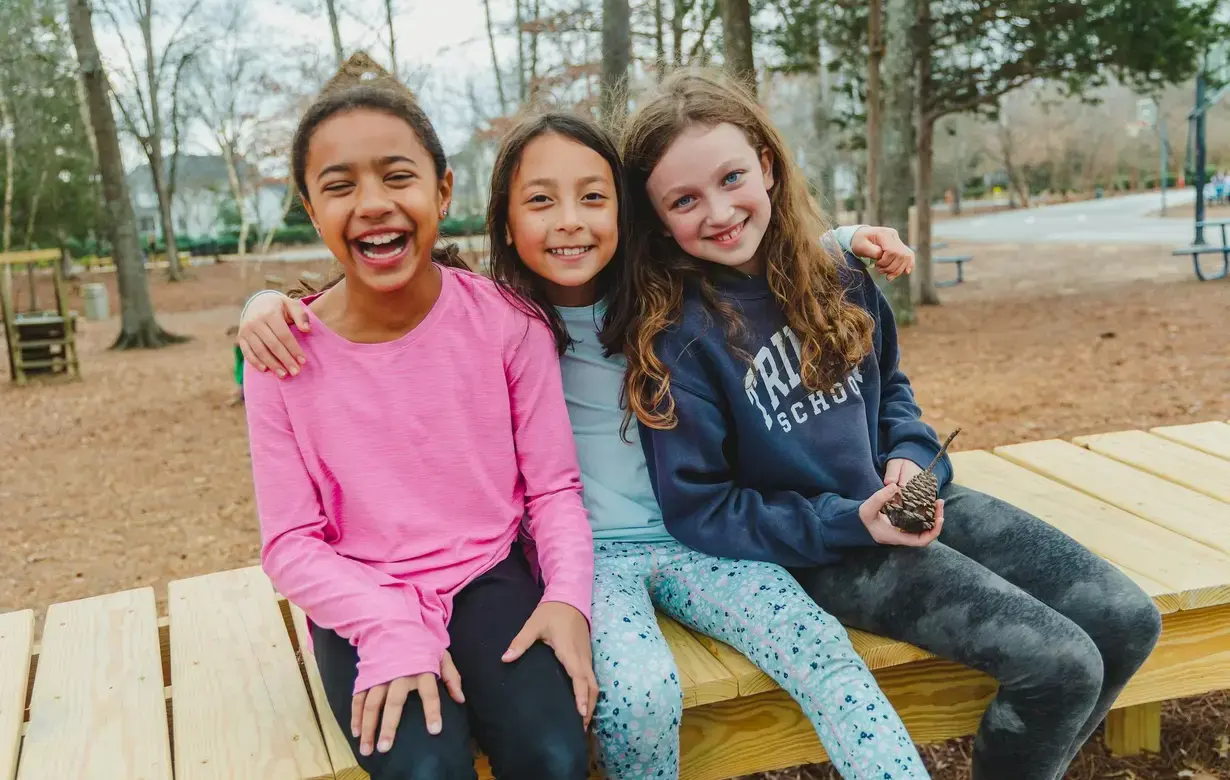 Three Trinity students sitting outside laughing