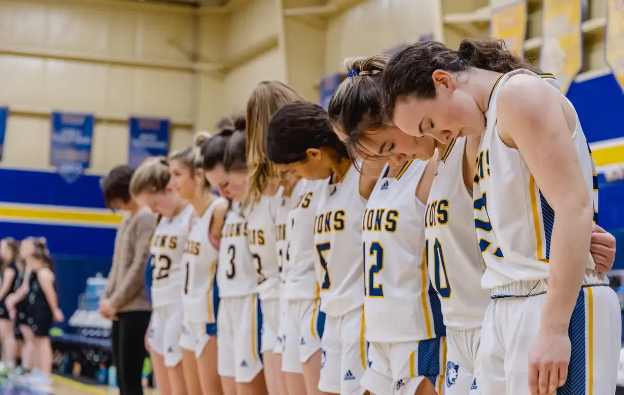 Varsity girls basketball bows heads in prayer before game