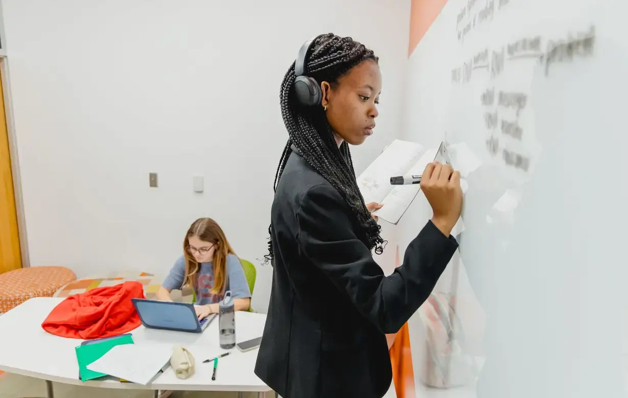 Trinity student working at whiteboard listening to music