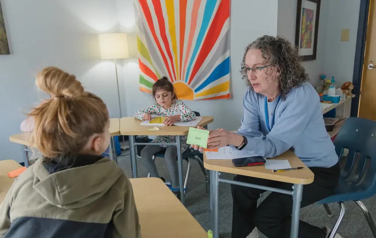 Interactive math lesson in a Trinity School Lower School classroom with a teacher engaging students using visual aids and hands-on materials, highlighting the school's supportive learning environment.