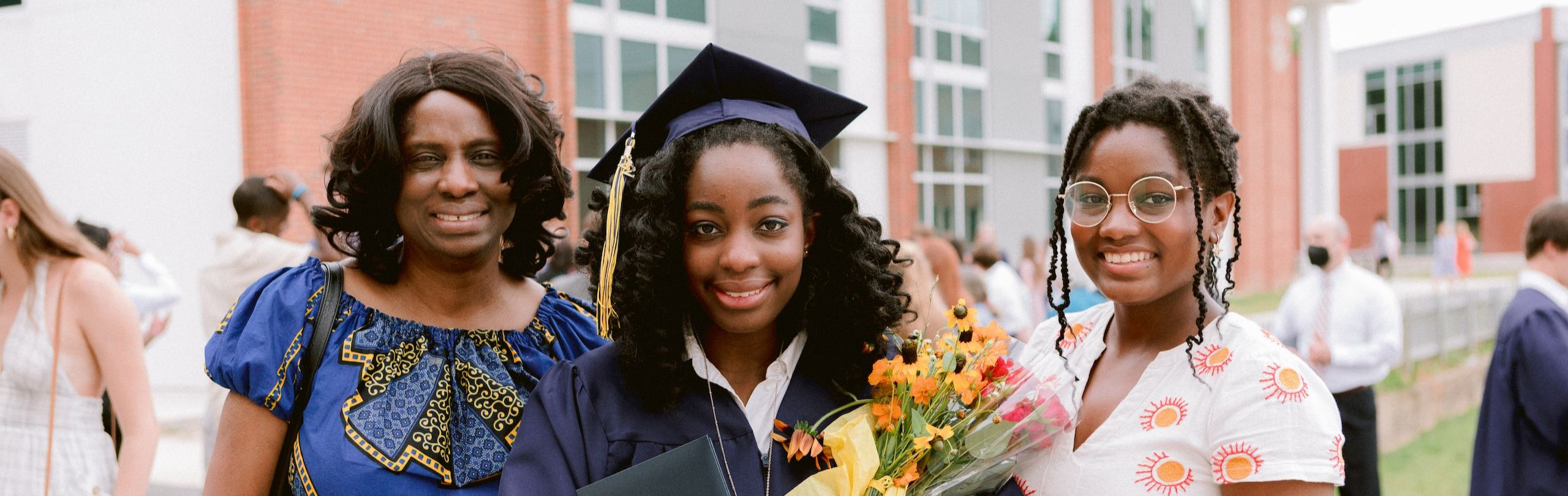 Trinity Upper School student with family at graduation holding flowers