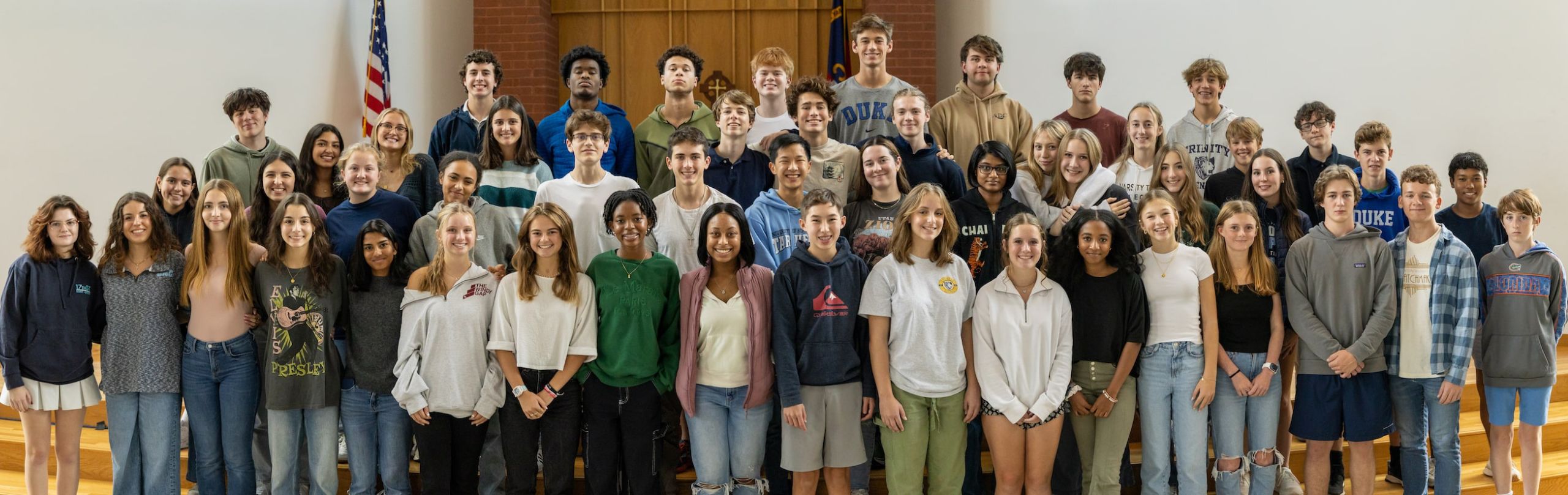 A diverse group of high school students smiling, gathered for a group photo in a school setting, representing the vibrant school community and student body.